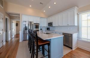 a kitchen with white cabinets and a island with bar stools at Hidden Treasure - Nags Head MP 16, Oceanfront, Private Beach Access, Pool, Hot Tub, Pool Table, Pets OK in Nags Head +62 photos