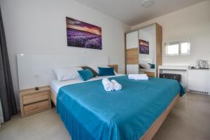 a bedroom with a large blue bed with towels on it at Pool Apartments & Rooms Mare in Novalja