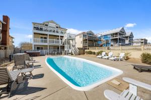 a swimming pool with chaise lounges and chairs at Atlantic Watch in Kill Devil Hills