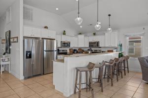 a kitchen with white cabinets and a bar with stools at Atlantic Watch in Kill Devil Hills +24 photos