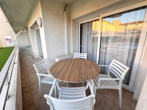 ein Holztisch und weiße Stühle auf einem Balkon in der Unterkunft El Foraió in L'Estartit