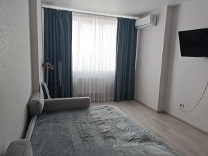 a bedroom with a bed and a large window at Квартира Одесская in Odesa