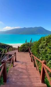 a wooden staircase leading to a beach with the ocean at Condomínio Aparte Hotel Laguna in Arraial do Cabo