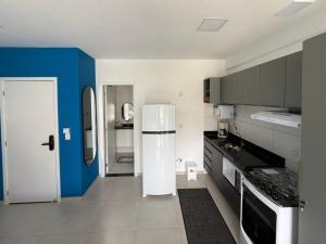 a kitchen with a white refrigerator and a blue wall at Condomínio Aparte Hotel Laguna in Arraial do Cabo