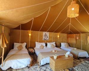 a room with three beds in a tent at Luxury Desert Central Camp in Merzouga