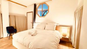 a bedroom with a large white bed with a window at - Magnifique appartement climatisé 92m2, spacieux et cosy, au cœur de Vichy in Vichy