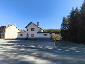a white house sitting on the side of a road at The Eau Rouge 600m from the entrance of the circuit in Stavelot