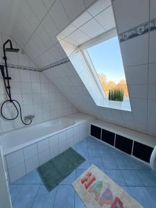 a bathroom with a bath tub and a window at Gemütliche Galeriewohnung im Grünen in Trappenkamp