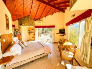a bedroom with a large bed and a table and a desk at Balcones de La Cumbrecita in La Cumbrecita