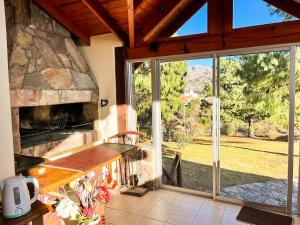 a kitchen with a stone fireplace and a large window at Balcones de La Cumbrecita in La Cumbrecita
