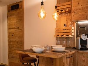 a kitchen with a wooden table with bowls and lights at SKY LOVE Luxury Chalet in Andalo +3 photos