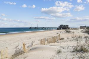 a sandy beach with a pier in the ocean at Pier View Oasis - Nags Head MP 16, Oceanfront, Elevator, Theater, Pool, Hot Tub, Pets OK in Nags Head
