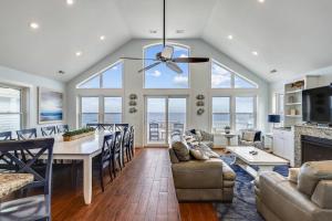 a dining room and living room with a table and chairs at Pier View Oasis - Nags Head MP 16, Oceanfront, Elevator, Theater, Pool, Hot Tub, Pets OK in Nags Head