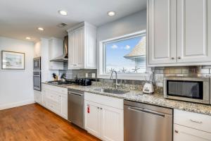 a kitchen with white cabinets and a window at Pier View Oasis - Nags Head MP 16, Oceanfront, Elevator, Theater, Pool, Hot Tub, Pets OK in Nags Head +79 photos