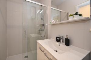 a white bathroom with a sink and a shower at Pool Apartments & Rooms Mare in Novalja +24 photos
