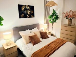 a bedroom with a bed with white sheets and brown pillows at Parenthèse lumineuse près de Disney, Parking privé in Montévrain