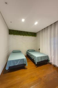 two beds in a room with wood floors at Studio para 7 pessoas com Ar Condicionado e 2 Garagem in Uberlândia