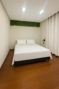 a bedroom with a large bed with white sheets at Studio para 7 pessoas com Ar Condicionado e 2 Garagem in Uberlândia