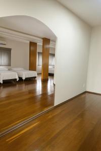 an empty room with two beds and a wooden floor at Studio para 7 pessoas com Ar Condicionado e 2 Garagem in Uberlândia