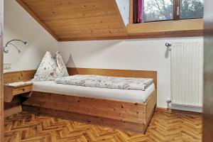 ein Bett in einem Zimmer mit Holzboden in der Unterkunft Ferienwohnung Marienkäfer Rückzugsort inmitten der Natur mit Bergblick in Klobenstein