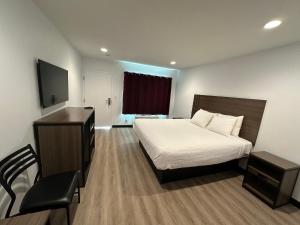 a bedroom with a bed and a desk and a television at Hyland Inn Van Nuys in Van Nuys