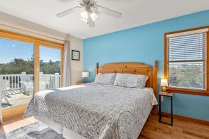 a bedroom with a bed with blue walls and a window at Anchors Away in Corolla +53 photos