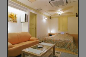 a living room with a couch and a bed at ホテルパークアベニュー in Nagoya
