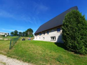 a white building with a black roof and a tree at Ferienwohnung Saupe in Königshain