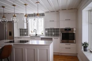 a kitchen with white cabinets and a sink and a microwave at Chalet l'Intemporel - St Lawrence View in Notre-Dame-du-Portage