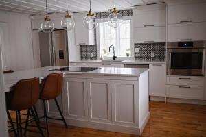 a kitchen with white cabinets and a kitchen island with chairs at Chalet l'Intemporel - St Lawrence View in Notre-Dame-du-Portage +27 photos