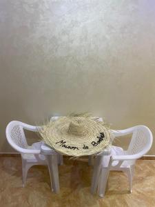 a straw hat sitting on a table with two chairs at maison de bonheur 2 in Tafraout +11 photos