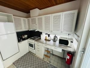a small kitchen with white cabinets and a microwave at The Zen Den Rokua in Utajärvi +9 photos