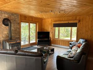 a living room with leather couches and a fireplace at Les Chalets du Lac Serein (Milot) in Saint Ludger de Milot