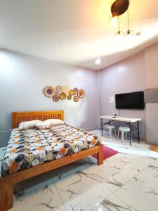 a bedroom with a bed and a desk and a tv at Aliyah Transient House in Atimonan