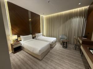 a hotel room with two beds and a desk at Afaq Royal Almassar Hotel ex Hayah Al Iman in Mecca +72 photos