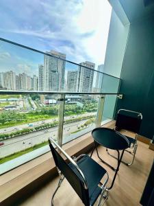 a room with two chairs and a table and a large window at Clasio - Lumiere Riverside in Ho Chi Minh City