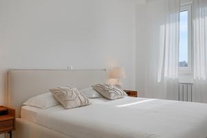 a bedroom with a white bed with two pillows at Fiorea Apartment - Pula City Center With Private Garage Parking in Pula
