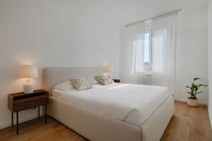 a white bedroom with a white bed and a window at Fiorea Apartment - Pula City Center With Private Garage Parking in Pula