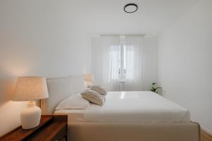 a bedroom with a large white bed with a lamp at Fiorea Apartment - Pula City Center With Private Garage Parking in Pula