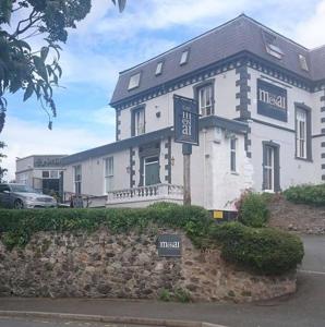 un gran edificio blanco con un cartel delante en The Menai Hotel and Bar, en Bangor