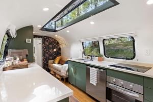 an rv kitchen with green cabinets and windows at Airstream w Bathtub, River, & Hot Tub in Pisgah Forest
