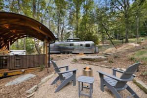 a camp site with two chairs and a trailer at Airstream w Bathtub, River, & Hot Tub in Pisgah Forest