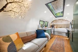 a living room with a couch and a bedroom at Airstream w Bathtub, River, & Hot Tub in Pisgah Forest