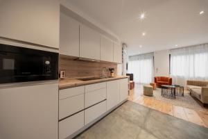 een keuken met witte kasten en een woonkamer bij The Suite Garden Hotel in Frankfurt am Main