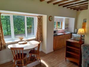 a kitchen with a table and chairs and windows at Nethergate Cottage, Westerclose, Withypool in Withypool