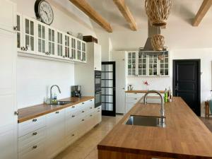 a kitchen with white cabinets and a clock on the wall at Beach Villa With Private Pier In Hou in Odder