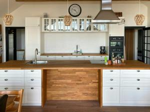 a kitchen with white cabinets and a wooden counter top at Beach Villa With Private Pier In Hou in Odder
