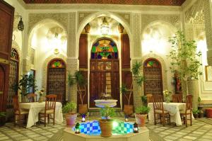 a room with tables and chairs and stained glass doors at Riad Sara in Fez