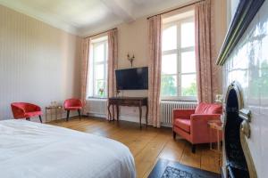 a bedroom with a bed and a desk and two chairs at Château de Looz in Borgloon