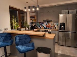 a kitchen with a counter and two blue bar stools at Paradise Vibe Balaton in Balatonkenese